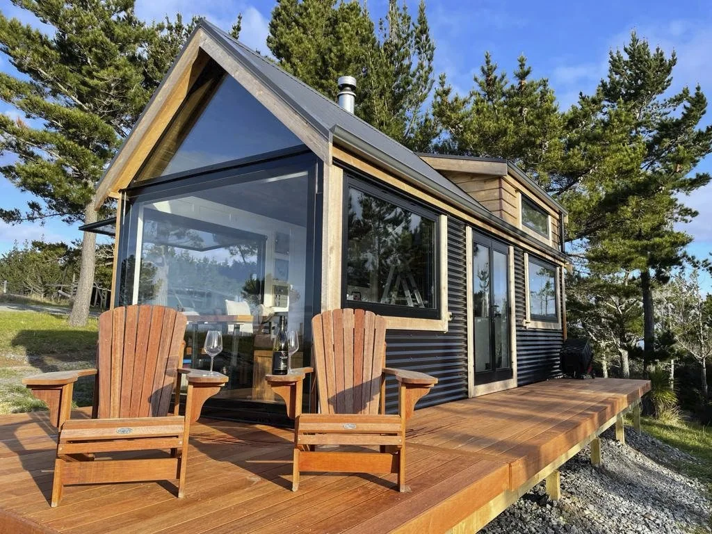 Tiny House mit Holzterrasse in grüner Umgebung
